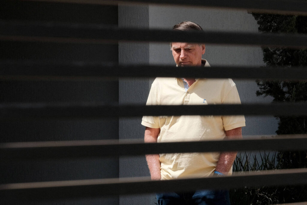 Homem em camisa amarela atrás de grades.